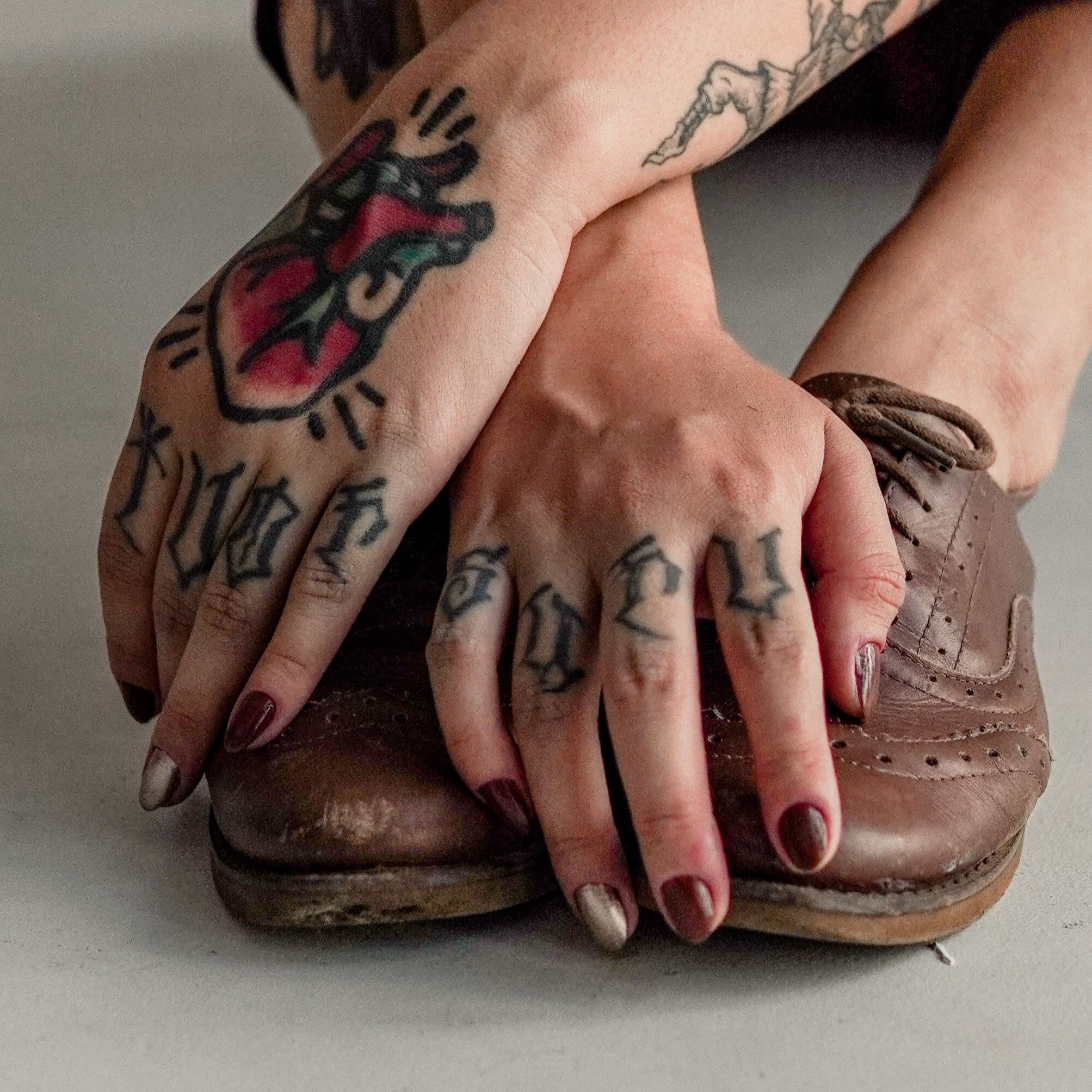 Mãos com tatuagem de coração em estilo old school